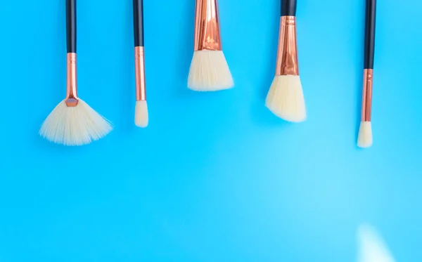 premium makeup brushes on blue background with shadows, creative cosmetics flat lay, tools for make up, copy space