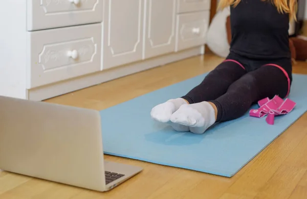 a girl gymnast trains at home via video connection on a laptop, remote sports