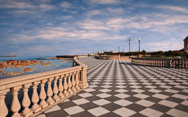 Leghorn (Livorno), Tuscany, Italy:  landscape at dawn of the promenade Mascagni Terrace, a picturesque seashore on the Ligurian sea with black and white checkered pavement and columned bannister clipart
