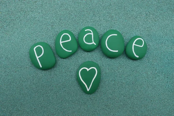 Peace word with green painted sea stones over green sand