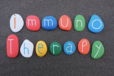 Immunotherapy text with multicolored stones over black volcanic sand clipart