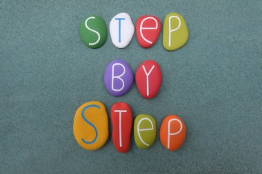 Adım adım yeşil kum üzerinde çok renkli taşlarla oluşturulmuş metinler