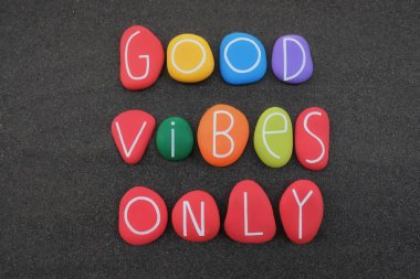 Sadece Good Vibes, siyah volkanik kum üzerinde çok renkli taş harflerle oluşturulmuş daha iyi bir yaşam için pozitif bir ifade.
