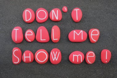 Söyleme, göster bana. Motivasyon cümlesi siyah volkanik kumların üzerine kırmızı renkli ve oyulmuş taş harflerden oluşur.