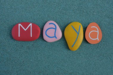 Maya, female given name composed with multi colored and carved stone letters over green sand clipart