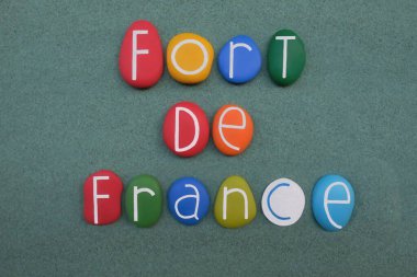 Fort-de-France, capital city of Martinique, an overseas department of France located in the Caribbean, souvenir with multi colored stone letters composition over green sand clipart