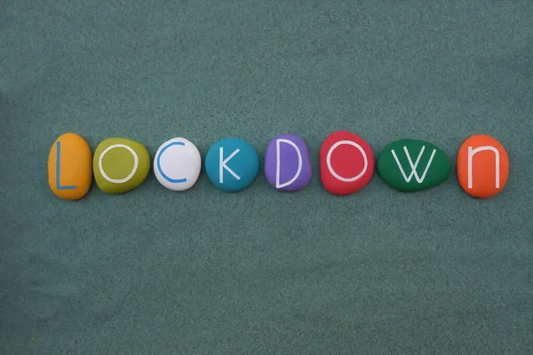 Lockdown Coronavirus, Pandemic world lockdown for quarantine composed with multi colored stone letters over green sand