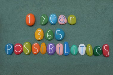 Bir yıl, 365 olasılık, ilham motivasyon motivasyonu, yeşil kum üzerinde çok renkli el yapımı taş harflerle bestelenmiş.