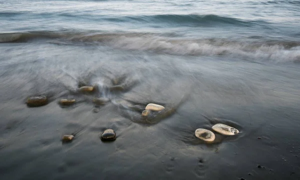 Kiezels in het strand en het stromende zeewater — Stockfoto