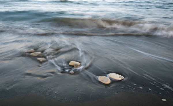 Kiezels in het strand en het stromende zeewater — Stockfoto