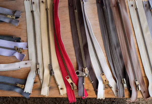 Worn used cloth zippers  on a wooden board — Stock Photo, Image