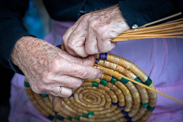 Seniorin strickt einen traditionellen Korb mit Schilf — Stockfoto