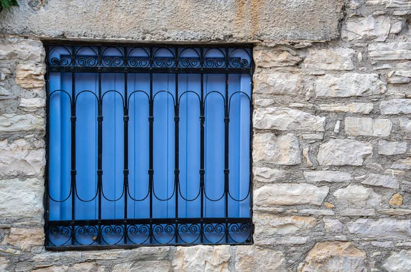 Blue wooden vintage window with a metal safety frame on a brick — Stock Photo, Image