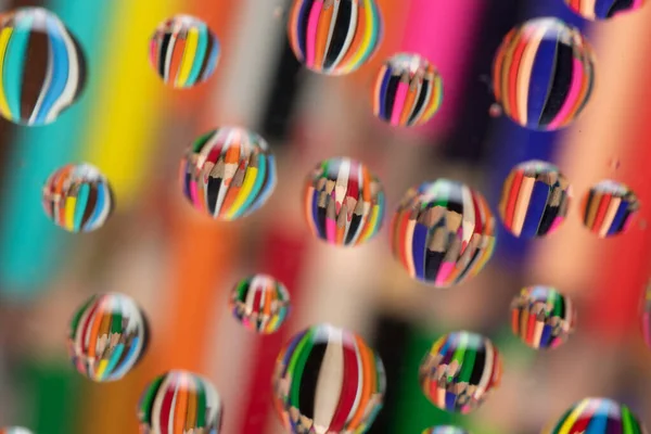 Drawing pencils reflected on waterdrops resting a piece of glass — Stock Photo, Image