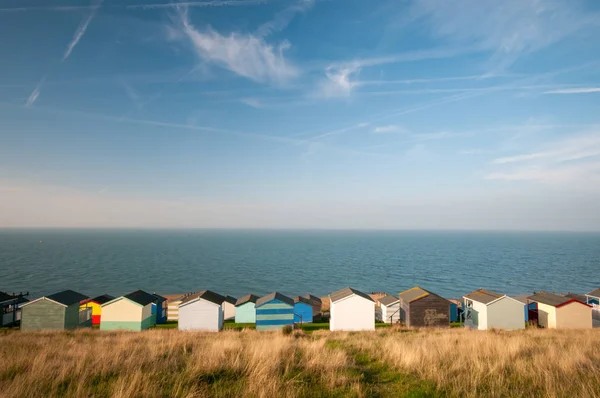 Colourful beach huts against a cloudy sky and facing the  sea. — Stock Photo, Image