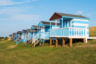 Whitstable sahilinde okyanusa bakan renkli ahşap plaj kulübeleri.