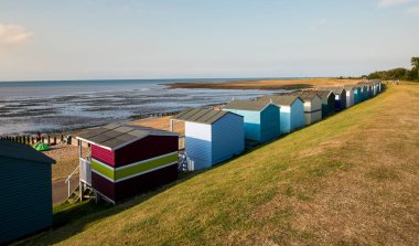 Whitstable sahilinde okyanusa bakan renkli ahşap plaj kulübeleri.