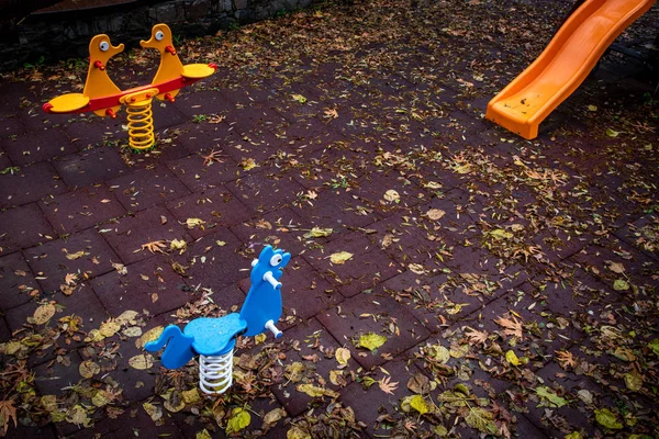 Prázdné dětské hřiště s barevnými hračkami a listy na — Stock fotografie