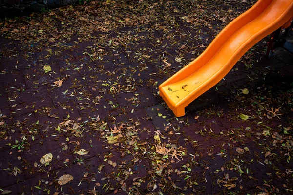 Пустая детская площадка с красочными игрушками и листьями на — стоковое фото