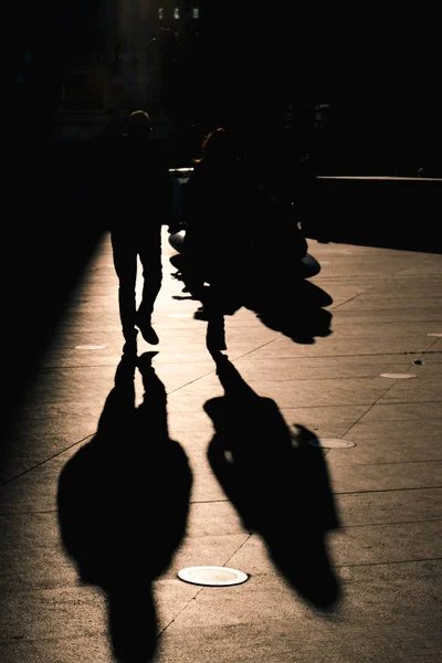 Unrecognised people walking with backlight creating strong shado — Stock Photo, Image