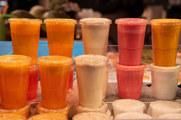 Műanyag poharak kevert friss gyümölcslevekből jégen — Stock Fotó