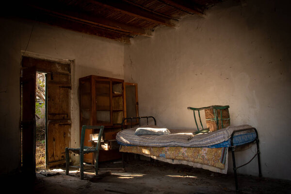 Interior of the bedroom of an abandoned room with bed, furniture and open door. Concept of demolition and Abandonment