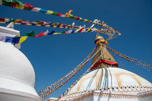 Boudha Stupa, at Kathmandu city in Nepal against blue sky, with religious colorful flags waving.