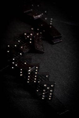 Siyah Domino blokları arka arkaya düşüyor, siyah arkaplanda izole.
