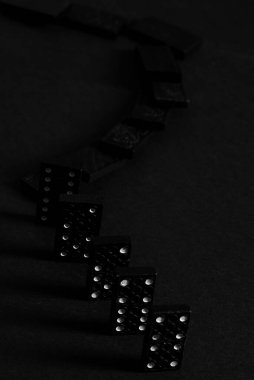 Siyah Domino blokları arka arkaya düşüyor, siyah arkaplanda izole.