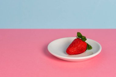 Beyaz tabakta taze kırmızı çilek ve renkli arka plan