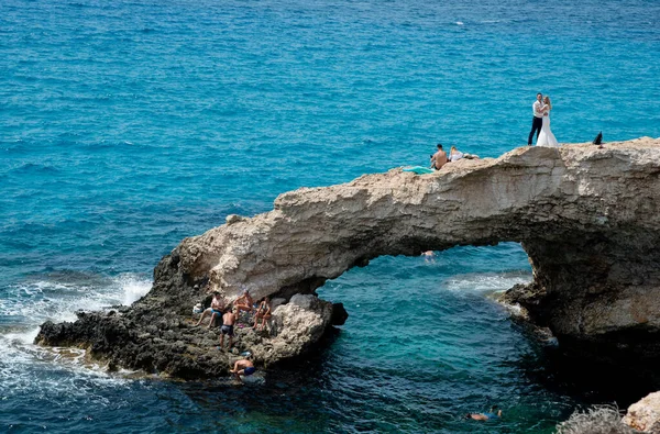 Agia Napa キプロス 2019年9月14日 結婚式の写真撮影中に若いカップルがキスをし 10代の若者がキプロスのAgia Napaにある象徴的な恋人の橋で泳いでいます — ストック写真