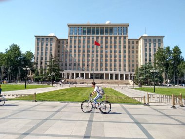 Pekin, Çin, Haziran 12018: Pekin 'deki ünlü Tsinghua Üniversitesi binasının ana girişinin önünde bisiklete binen öğrenciler