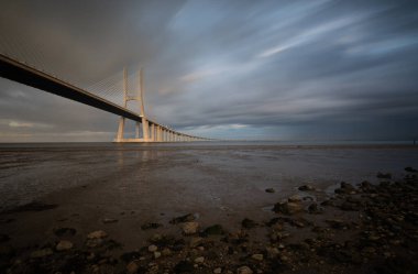 Vasco da Gama Köprüsü, gün batımında Lizbon Portekiz 'de bulutlu bir gökyüzüyle. Uzun pozlama fotoğrafı