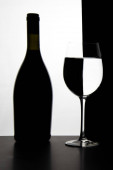 Černá láhev a prázdná sklenice vína na bílém a černém pozadí