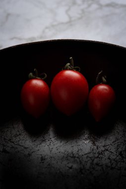 Siyah bir tavada izole edilmiş kırmızı sağlıklı domatesler.