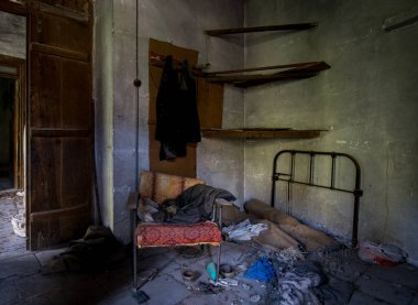 Hasarlı mobilyaları ve dağınık zemini olan terk edilmiş eski bir yatak odasının içinde.