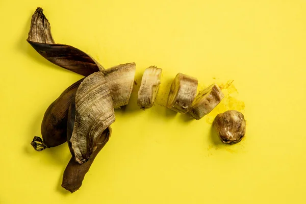 Slices of rotten unhealthy banana on a yellow background
