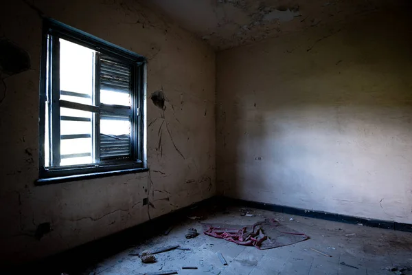 Interior of an old abandoned bedroom with damaged furniture and a messy floor