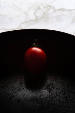 Siyah bir tavada izole edilmiş kırmızı sağlıklı domatesler.