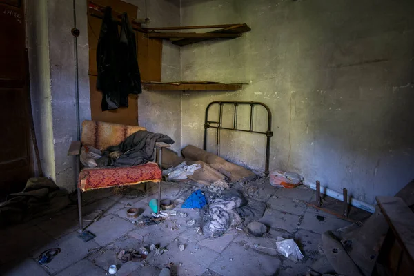 損傷した家具と乱雑な床と古い放棄されたベッドルームのインテリア — ストック写真