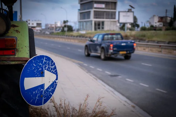 Blue directive road sing post warning on a highway and car on the road