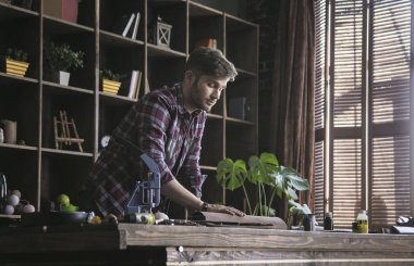 Genç adam deri işçi iş Studio'da deri yeni rulo ahşap masa üzerinde tutun