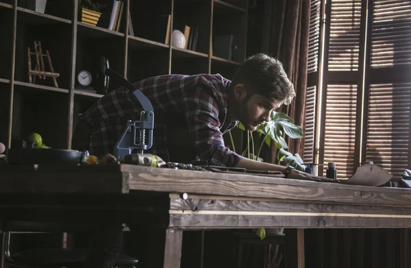 Genç erkek deri yapan deri tam boyutları workwooden masanın üzerine alır.