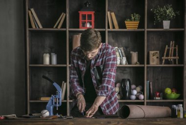 Deri üreticisi çalışma ve deri kesme parça genç adam