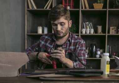 Deri maker deri şablonları ile ahşap masa oturan genç adam