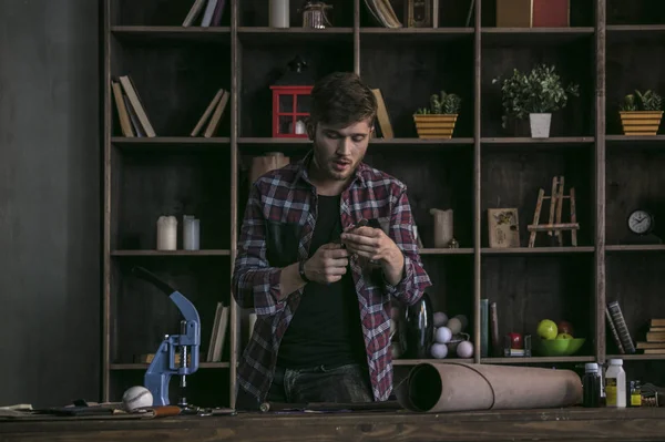 Genç deri üreticisi ayakta ahşap masa önünde adam ve şerit kesme