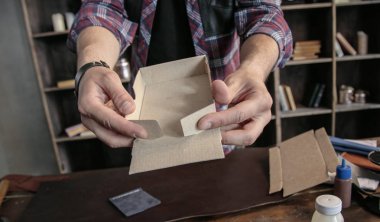 Young man leather maker manually assemble cardboard packaging box for products