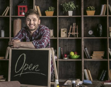 Araçları ile masada açık işareti yakın duran genç gülümseyen adam deri işçisi