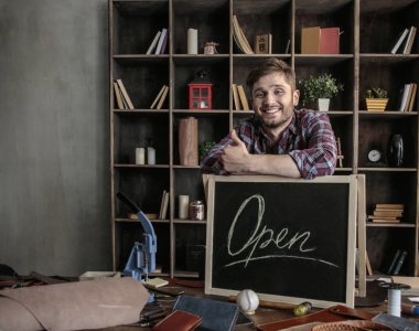 Açık ahşap masa tabelaya yakın duran genç neşeli adam deri işçisi