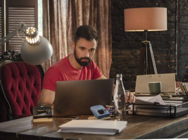 Başlangıç karanlık stüdyoda oturan ve dizüstü bilgisayarda çalışan genç işadamı